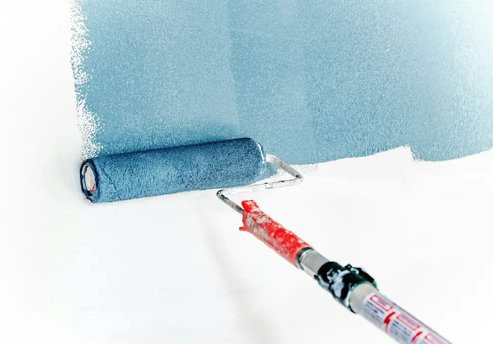 Pièce en cours de peinture intérieure avec rouleau et bâches de protection
